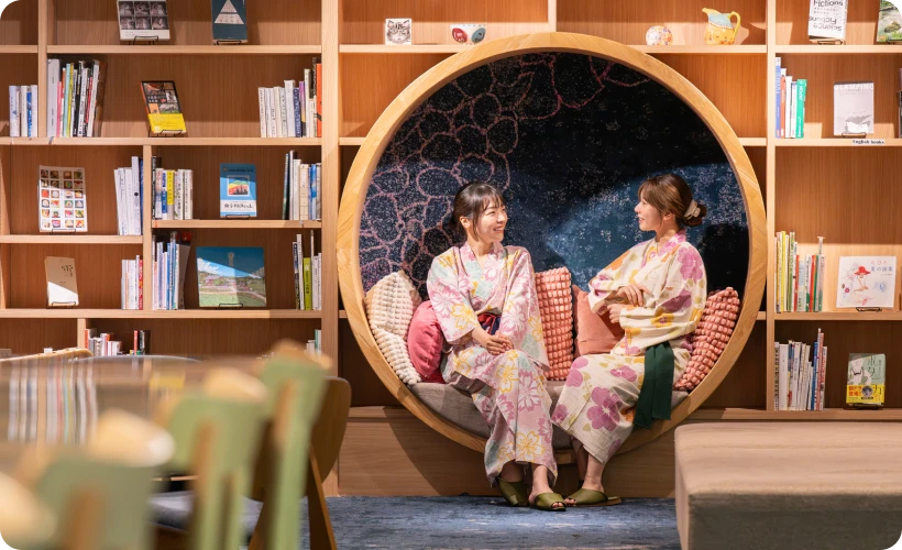 本棚の円形スペースで本を読む浴衣姿の女性